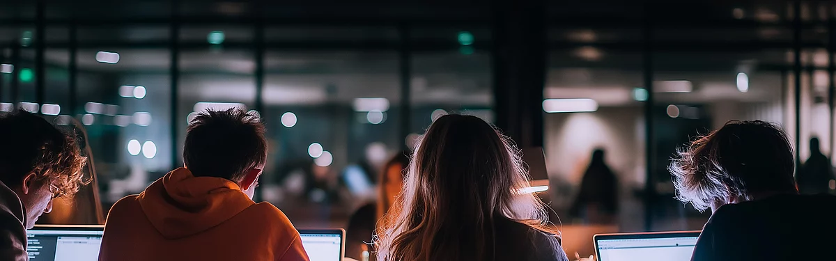 Mehrere Personen arbeiten nebeneinander an Laptops im modernen Büro – Agenturjobs und Karriere